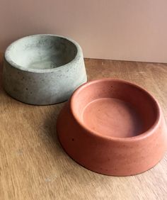 two clay bowls sitting on top of a wooden table next to each other and one is empty