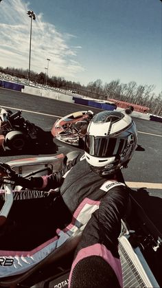 two motorcyclists sitting in the middle of a race track with helmets on