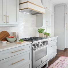 a kitchen with white cabinets and an oven in the center, along with a pink rug on the floor