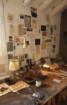 an old desk with lots of papers on the wall next to it and a lamp