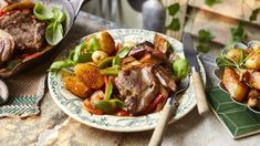 two plates filled with meat and vegetables on top of a table next to silverware