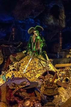 a skeleton sitting on top of a pile of gold in a cave with other items