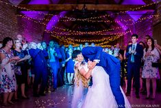 a bride and groom kissing in front of their wedding party at the end of an aisle