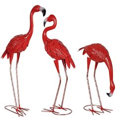 two red flamingos standing next to each other on metal bases with long legs and feet