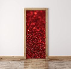 an open door with red glitter on it in front of a white wall and wooden floor