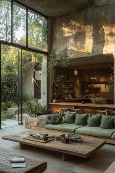 a living room filled with lots of furniture next to a large glass wall covered in greenery