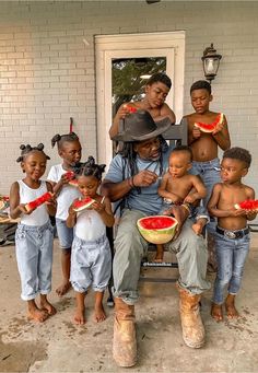 a man sitting on top of a chair with children eating watermelon