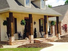 the front porch of a house with rocking chairs and potted plants on the steps