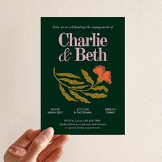 a person holding up a card that says charlie and beth on the front with an orange flower