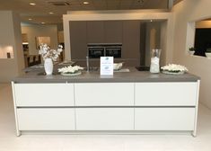 a kitchen with white cabinets and flowers in vases on the counter top next to an oven