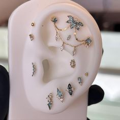 there are many different types of ear piercings on this white display stand in front of a black chair