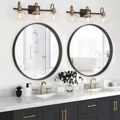 two round mirrors on the wall above double sinks in a white bathroom with gold accents