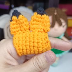 a hand holding a small crocheted object in it's left hand and another toy on the other side