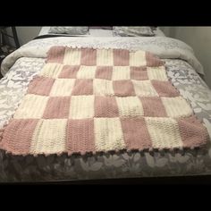 a pink and white blanket on top of a bed