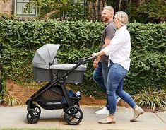 a man and woman walking with a baby in a stroller