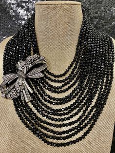 "Heidi Daus Best In Bows Crystal Accented 13 Strand Black Bib Necklace Swarovski Crystals BIG, BOLD & BEAUTIFUL Statement piece fit for a queen! Absolutely Magnificent. This necklace features 13 strands of black faceted beads. An asymmetrically placed bow in clear round and black diamond Swarovski crystals lies on the side of this necklace. Certainly not for the timid, but a showstopper for sure. It will have people swarming around you to get a glimpse of this piece of art. Approx 19\" with Black Diamond Necklace, Necklace Swarovski, Heidi Daus, Double Strand Necklace, Enamel Beads, Diamond Jewelry Necklace, Bib Necklace, Strand Necklace, Jewellery Making