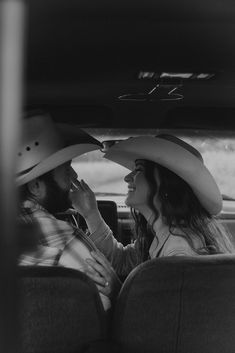 a man and woman sitting in the back seat of a car with hats on their heads