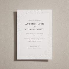 an elegant white wedding card with the word, and floral design on it's front