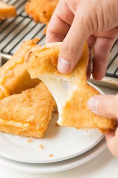 someone is holding up some fried food on a white plate and it looks like they are going to eat something out of the oven