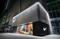 the nike store is lit up at night with its logo on it's side