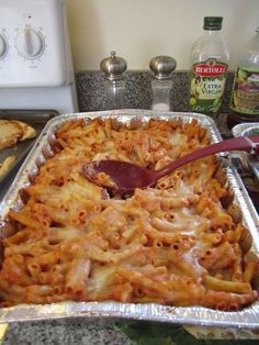 a pan filled with pasta and sauce on top of a counter next to an oven