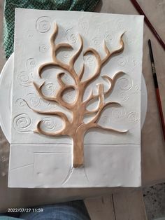 a white paper with a tree on it and some paintbrushes next to it