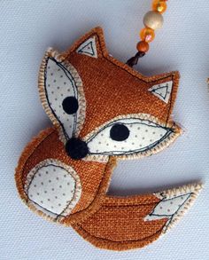 a fox ornament is hanging from a beaded necklace