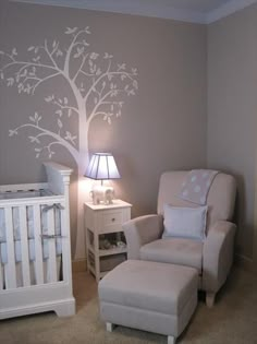 a baby's room with a tree painted on the wall and a white crib