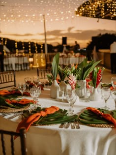 the table is set with white and orange napkins, silverware, and flowers