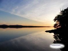 the sun is setting over a calm lake