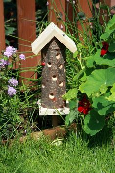 a bird house sitting in the grass next to flowers