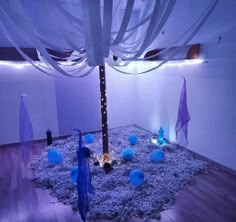 the room is decorated with blue and white balls, streamers, and lights on the floor