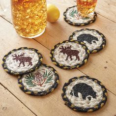 four embroidered coasters with bears and pineapples on them next to a glass of beer