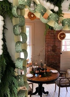 a table and chairs in a room decorated with christmas garlands, candles and decorations