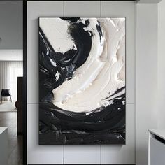 an abstract black and white painting hangs on the wall in this modern living room area