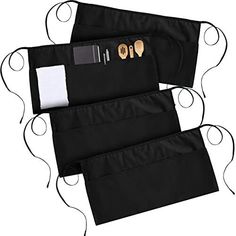 two black aprons with wooden utensils in them and one has a white pocket