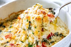 a casserole dish with spinach and cheese being lifted from the casserole