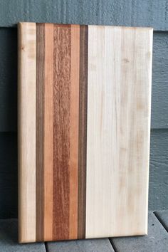 a wooden cutting board sitting on top of a tile floor next to a building wall