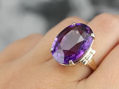 This is a stunning stone, with a rich color and a sophisticated cut. This natural, well-cut amethyst at the center glimmers with its medium-deep eggplant purple color that flashes with pops of violet and raspberry. We've set this pretty gem into a vintage mounting of yellow gold. Easy to wear, this sits comfortably on the finger and is a nice, bold size that is sure to make a statement! Metal: 14K Yellow Gold Gem: Amethyst 19.50 Carats Gem Measurements: 15.9 x 20.8 mm, Oval Ring Size: 5.50 Marks Oval Stone Ring, Amethyst Cocktail Ring, Gold Drop Necklace, Beautiful Rings Vintage, Big Stone Ring, Right Hand Ring, Pearl Jewelry Design, Special Ring, Right Hand Rings