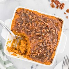 a casserole dish filled with mashed sweet potatoes and topped with pecans