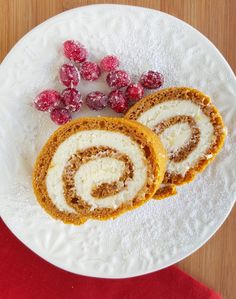 two rolls on a plate with raspberries and powdered sugar in the middle