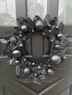 a wreath with silver ornaments hanging on the front door's glass paneled door