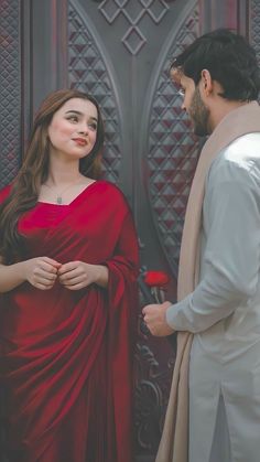 a man standing next to a woman in a red dress