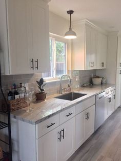 a kitchen with white cabinets and marble counter tops