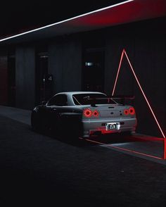 a white car parked in front of a building with red lights on it's sides