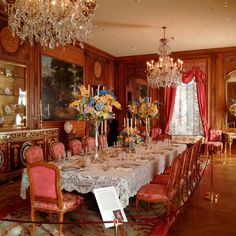 a fancy dining room with chandelier and table set for four people, all dressed in pink