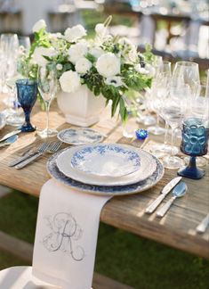 the table is set with blue and white plates, silverware, and napkins