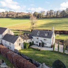 an aerial view of a large white house with trees in the foreground and fields behind it