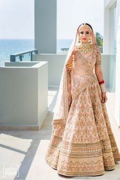 a woman in a bridal gown standing on a balcony with the ocean in the background