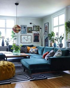 a living room filled with furniture and lots of plants on the wall next to a window